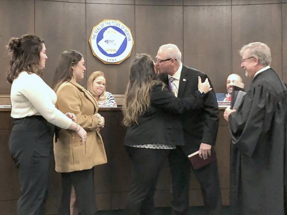 Councilwoman Helen Le Frois’s husband, Gregory, kisses her after she is sworn in. From left are her daughters Kathryn and Madelyn.