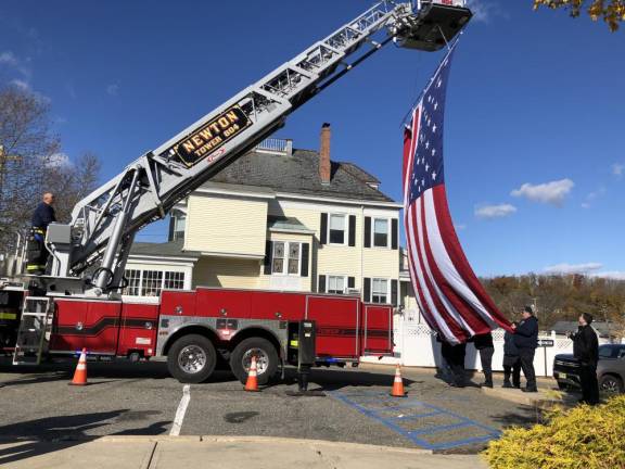 A huge American flag is hung from a Newton Fire Department ladder truck.