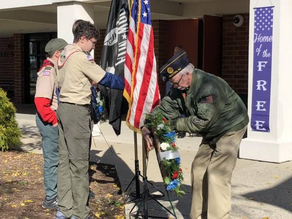 A member of the American Legion Post 86 Honor Guard presents a wreath.