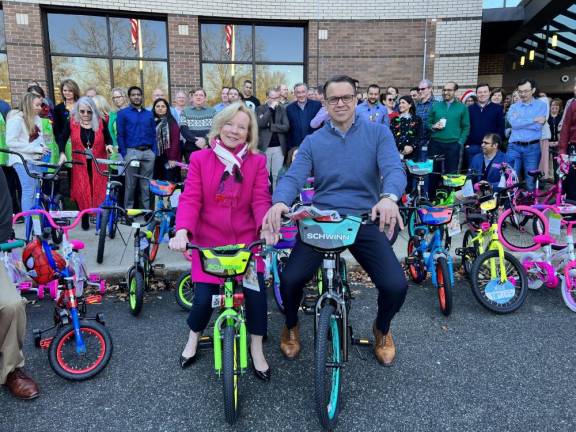 John Marchioni, chairman, president and chief executive of Selective Insurance, and Deborah Berry-Toon, executive director of Project Self-Sufficiency, pose on children’s bikes assembled by more than 200 employees Dec. 13 at the company’s Branchville headquarters. (Photo provided)