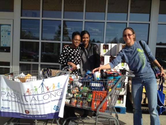 Pass It Along volunteers Virginie Amededji and Bianca Williams collecting food outside the Sparta Stop and Shop and Sparta resident Patricia Volin adding her contribution to the food drive.
