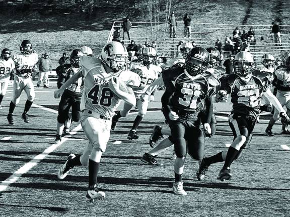 Silver running back Justin Lisinsky (48) on the move with purple defenders in hot pursuit in the pee wee game.