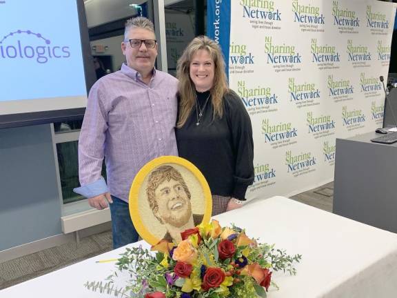 Heather and John Prutzman, mother and stepfather of organ and tissue donor Joseph ‘Joey’ C. Savage IV, stand behind a floragraph tribute to him that will be featured on the 2023 Donate Life Rose Parade float during the 2023 Rose Parade in Pasadena, Calif., on Jan. 2.
