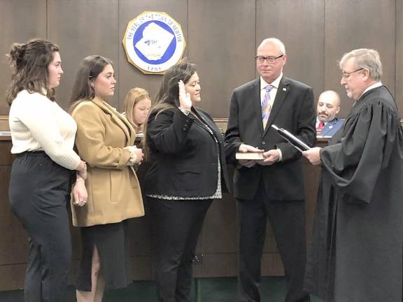Councilwoman Helen Le Frois takes the oath of office for her third term. From left are her daughters Kathryn and Madelyn and her husband, Gregory.