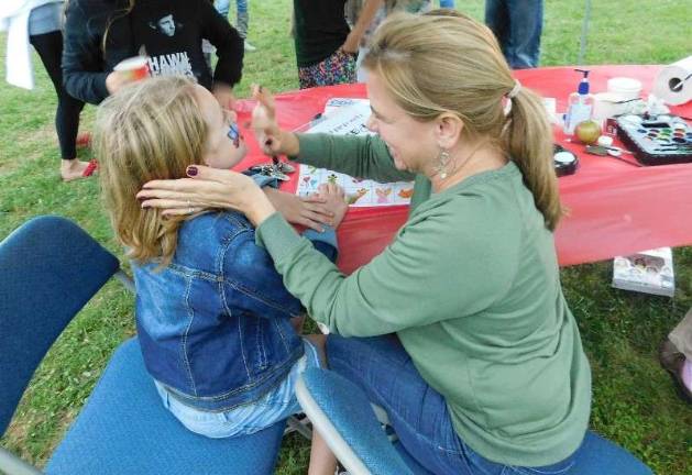 FMB paraprofessional Mindy Ducharme applies the finishing touches on a butterfly at the face-painting booth at the Andover Regional PTA Ice Cream Social Photos by Mandy Coriston