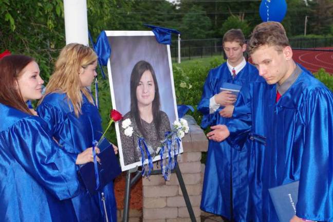 Second from left Kelsey Taylor Barker looks at her sister Lindsay Paige Barker's portrait as fellow graduates pay their respects inside the Memorial Garden on campus. Lindsay Paige Barker would have graduated in 2015 but died in 2014.