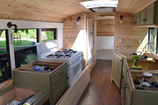 Photo by Erika Norton The inside of the "skoolie" features three couch/beds, a stove, a sink, cabinets, a full shower and a composting toilet.