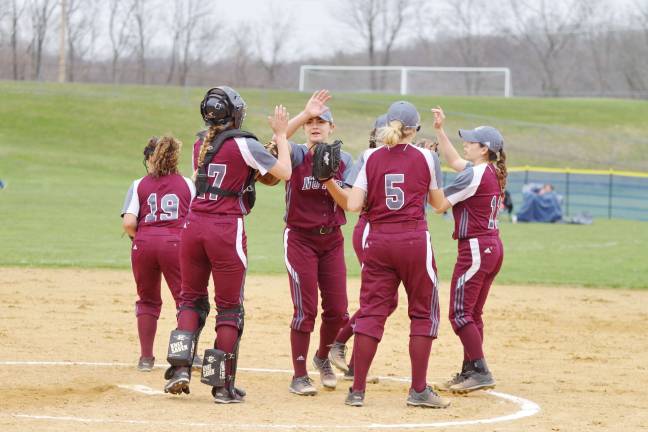 The Nutley Maroon Raiders high five each other on the mound before the start of an inning.