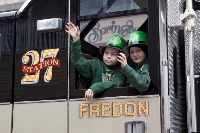 Two boys wave from the window of one of the Fredon Fire Department trucks.