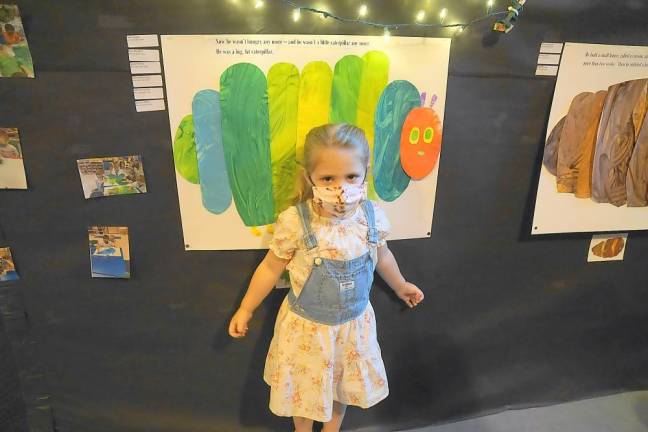 Olivia stands in front of the big caterpillar she helped paint (Photo by Vera Olinski)