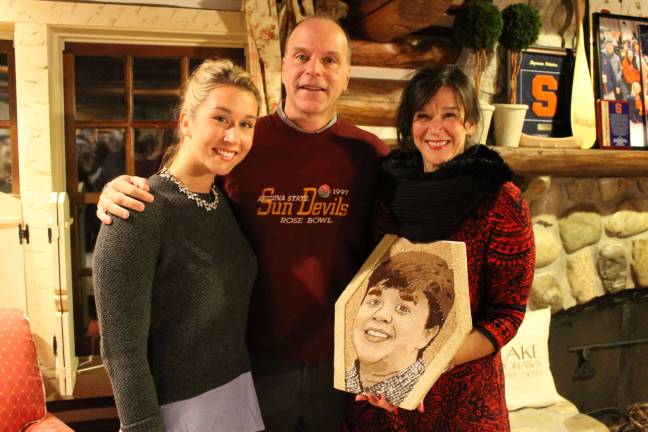 Isak's family, from left, sister Ellen Anderson, father Tom Anderson and mother Kylen Anderson, with the floragraph made in Isak's memory.
