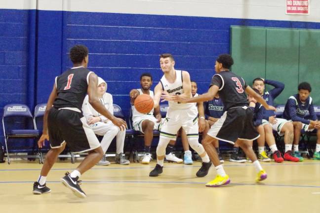 Sussex County basketball player George Mendez with the ball while covered by a pair of Passaic County defenders.