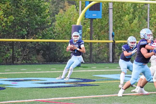 <b>Sparta quarterback Shane Hoover is about to throw while his teammates hold back the opposition. He passed for 297 yards and four touchdowns.</b>