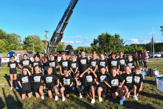 Members of Newton Braves Youth Cheerleading pose in front of a Newton firetruck at the 2025 Pep Rally on Thursday, Aug. 28 at Moran Park.