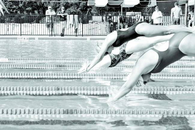 Photos By Robert OsZUST Swimmers dive into the water at the start of the first heat of the 100-yard freestyle event.