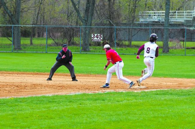 An official calls the Newton runner out at first base during a varsity baseball game between Newton and Lenape Valley.