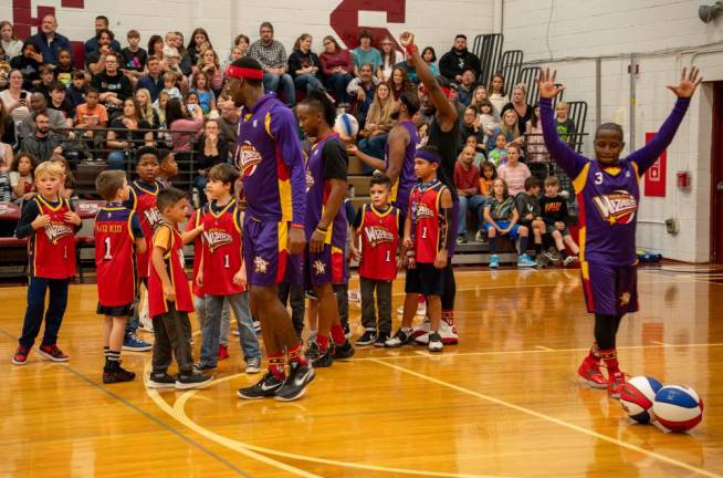 The Wiz Kids, wearing Harlem Wizards jerseys, join the players on the court.
