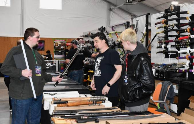 Vendors Pete Russo, center, and Damian Norman, right, talk to Kevin Forrester of Parsippany about the swords on display. (Photo by Maria Kovic)