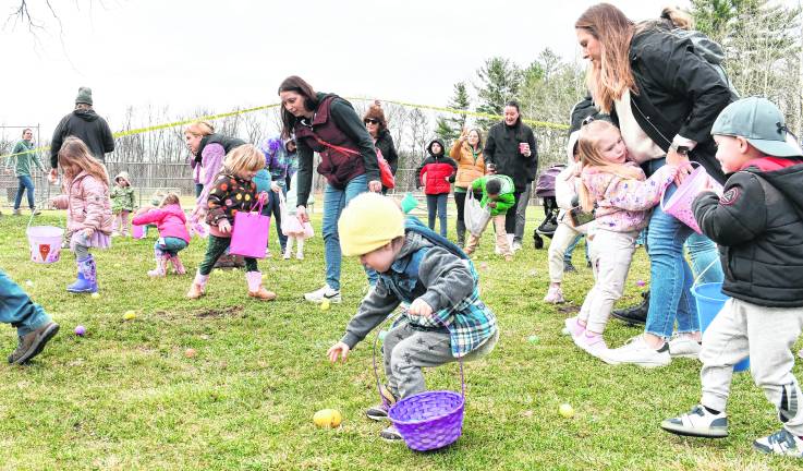Children pick up Easter eggs, some with the help of their parents.