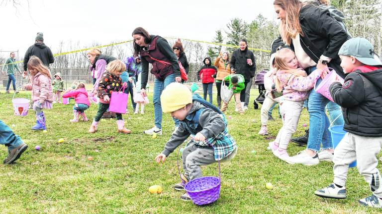 Children pick up Easter eggs, some with the help of their parents.