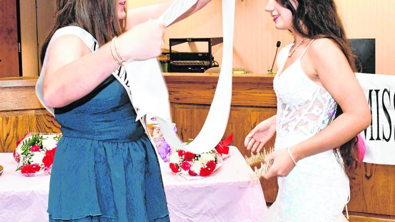 Miss Andover 2025 Chesney Walsh puts the sash on Miss Andover 2026 Sadie Fagerlin.